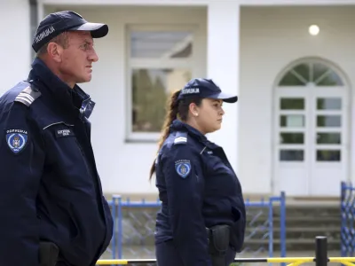 Police officers stand guard next to the schoolyard in the village of Dubona, some 50 kilometers (30 miles) south of Belgrade, Serbia, Friday, May 5, 2023. A shooter killed multiple people and wounded more in a drive-by attack late Thursday in Serbia's second such mass killing in two days, state television reported. (AP Photo/Armin Durgut)