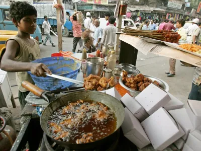 Saddam, 13, works at a roadside food stall in the eastern Indian city of Kolkata October 10, 2006. A ban on child labour in households, restaurants, hotels and resorts came into effect in India on Tuesday. Officials hope the new ban, which will apply to children under 14, will protect underage workers from psychological and sexual abuse as well as from strenuous working conditions. REUTERS/Parth Sanyal (INDIA)