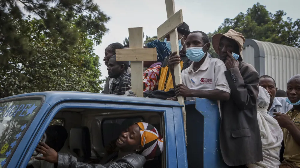 Relatives ride in the back of a truck with the coffins of villagers who were killed by suspected rebels as they retreated from Saturday's attack on the Lhubiriha Secondary School, outside the mortuary of the hospital in Bwera, Uganda Sunday, June 18, 2023. Ugandan authorities have recovered the bodies of 41 people including 38 students who were burned, shot or hacked to death after suspected rebels attacked the school in Mpondwe near the border with Congo, according to the local mayor. (AP Photo/Hajarah Nalwadda)