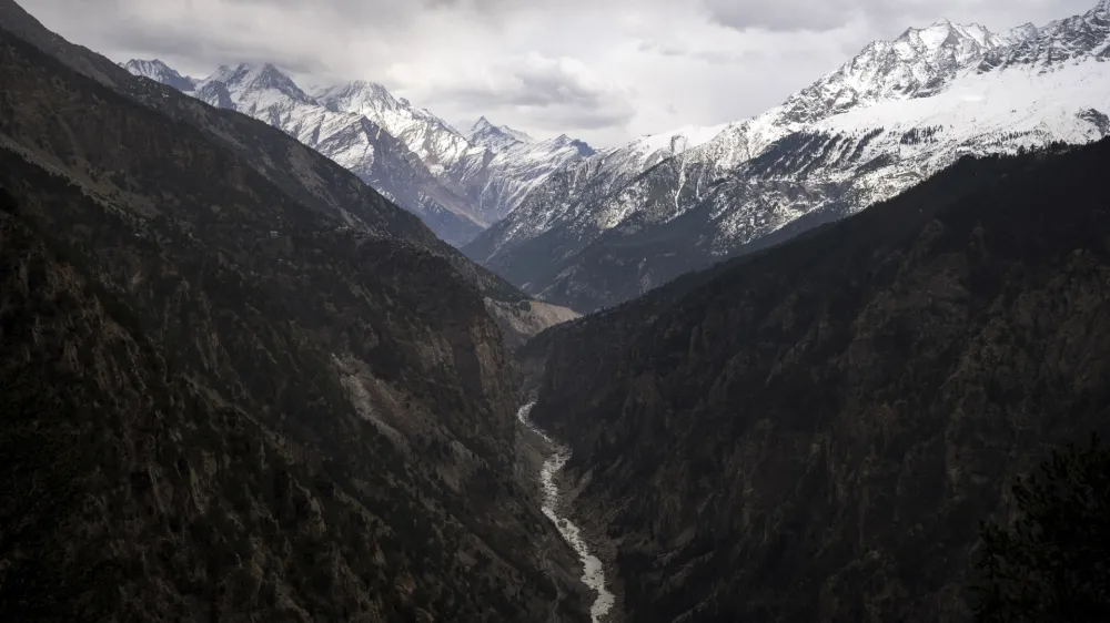 FILE - The Sutlej River flows in the valley below the tall snowy peaks in the Kinnaur district of the Himalayan state of Himachal Pradesh, India, March 13, 2023. A new report Tuesday, June 20, from a Nepal-based research organization finds that water security for nearly 2 billion people living downstream of rivers that originate in the Himalayan ranges will likely be threatened by the end of this century due to rapid glacier melt if global warming is not controlled. (AP Photo/Ashwini Bhatia, File)