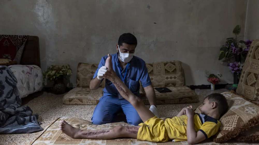 20 June 2023, Syria, Idlib: A medical volunteer from the Specialized Center for Rehabilitation and Physiotherapy follows up on the treatment of Mohammed Ghannam, 6 years old, who suffers from Crush Syndrome as a result of the earthquake. The medical team works to help and rehabilitate people with serious injuries such as amputation of limbs and crush syndrome in order to rely on themselves and receives 2000 cases per month. Photo: Anas Alkharboutli/dpa