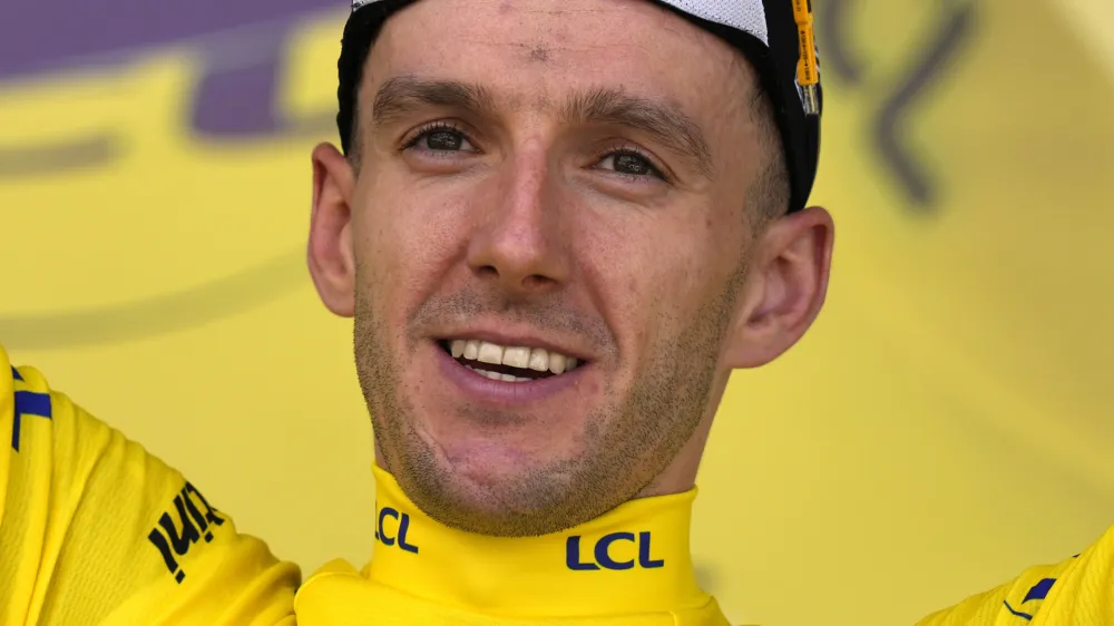 Britain's Adam Yates wearing the overall leader's yellow jersey, celebrates on the podium of the first stage of the Tour de France cycling race over 182 kilometers (113 miles) with start and finish in Bilbao, Spain, Saturday, July 1, 2023.. (AP Photo/Thibault Camus)