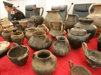 An Italian carabinieri officer watches over a table filled with stolen artefacts recovered in during operation at a police station in Rome October 7, 2005. Italian police said on Friday they had busted an international antiquities crime ring masterminded by an 82-year old Austrian tour guide known as Mozart. In a cross-border operation, police arrested five Italian tomb raiders and traced some 3,000 archaeological treasures to Mozart's Austrian home, mostly looted from sites near Rome. REUTERS/Chris Helgren