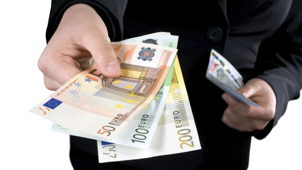 Hand giving Euro banknotes of 50, 100 and 200 Euro with another hand in the background keeping the spare. Isolated.Studio shot.