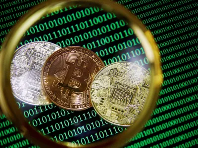 FILE PHOTO: Representations of Bitcoin and other cryptocurrencies on a screen showing binary codes are seen through a magnifying glass in this illustration picture taken September 27, 2021. REUTERS/Florence Lo/Illustration/File Photo