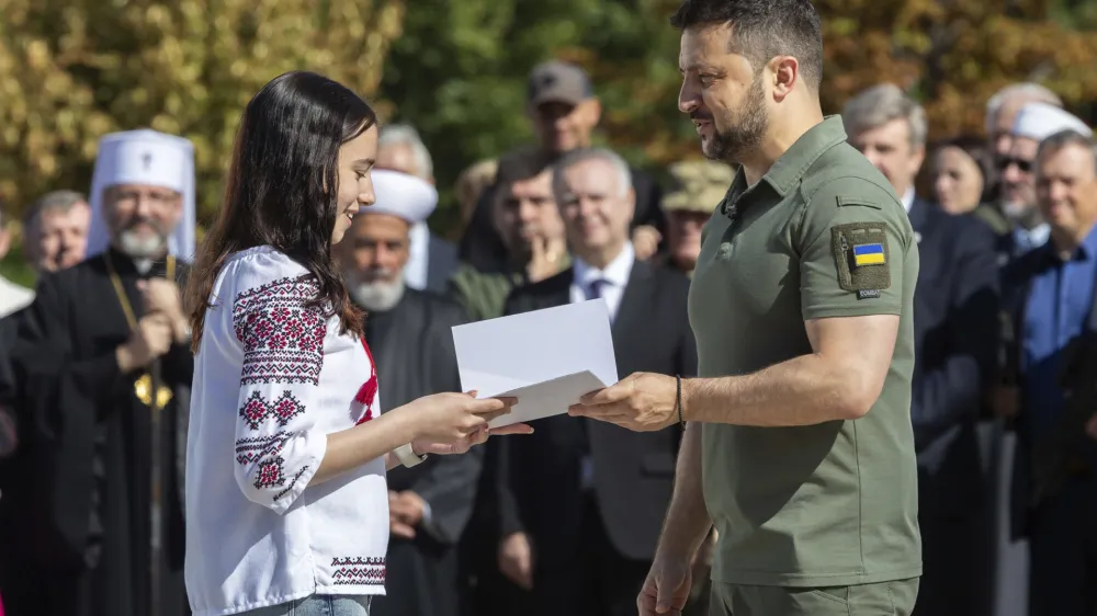 In this photo provided by the Ukrainian Presidential Press Office, Ukrainian President Volodymyr Zelenskyy, right, hands over the first passport for a girl during an event for marking Statehood Day in Mykhailivska Square in Kyiv, Friday, July 28, 2023. (Ukrainian Presidential Press Office via AP)