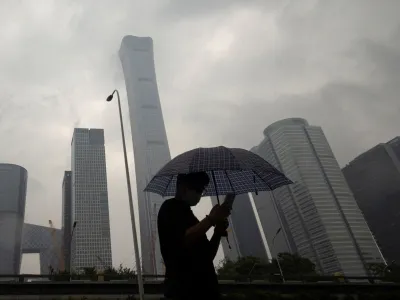 FILE PHOTO: A man walks in the Central Business District on a rainy day, in Beijing, China, July 12, 2023. REUTERS/Thomas Peter/File Photo