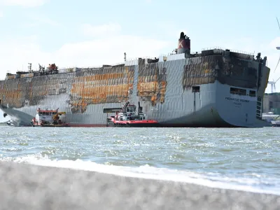 03 August 2023, Netherlands, Eemshaven: The badly damaged car carrier "Fremantle Highway" lies in the harbor. A good week after a fire broke out, the approximately 200-meter-long ship had been towed for hours to the North Sea port at the mouth of the Ems River. Photo: Lars Penning/dpa