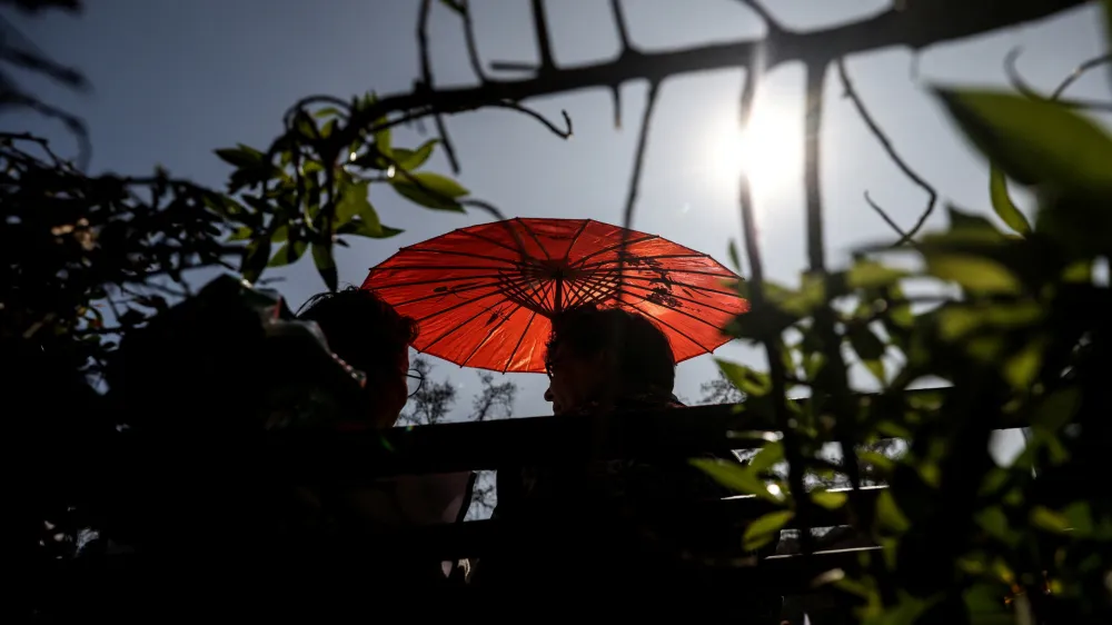 A woman uses an umbrella during an unusual winter period heatwave in Santiago, Chile, August 3, 2023. REUTERS/Ivan Alvarado