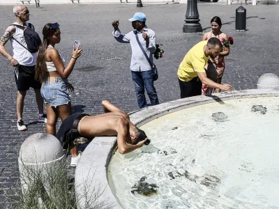 Tourists cool off at a fountain in Rome's Piazza del Popolo, as the African anticyclone is rising temperatures again all over Italy, starting a new heat wave. (Cecilia Fabiano/LaPresse via AP)