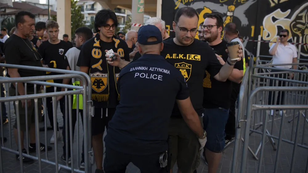 A police officer checks a soccer fan prior to the Champions League third qualifying round match between AEK Athens and Dinamo Zagreb, in Nea Philadelphia suburb, Athens, Greece, Saturday, Aug. 19, 2023. UEFA president Aleksander Ceferin met with Greece's prime minister Kyriakos Mitsotakis on Wednesday and promised to do more to deal with organized violence in soccer in the wake of a deadly attack led by Croatian fans in Athens. (AP Photo/Michael Varaklas)