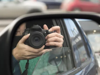 Hidden photographing. Reflection in car mirror of woman with camera. Paparazzi concept