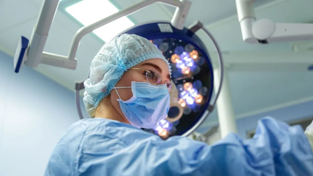 ﻿Female Doctor in Surgery Operating Hospital Room. Surgeon medic in protective work wear gloves, mask and cap.