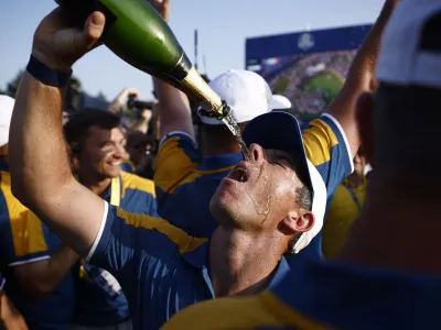 Golf - The 2023 Ryder Cup - Marco Simone Golf & Country Club, Rome, Italy - October 1, 2023 Team Europe's Rory McIlroy pours sparkling wine over his face on the 18th green as he celebrates after winning the Ryder Cup REUTERS/Guglielmo Mangiapane