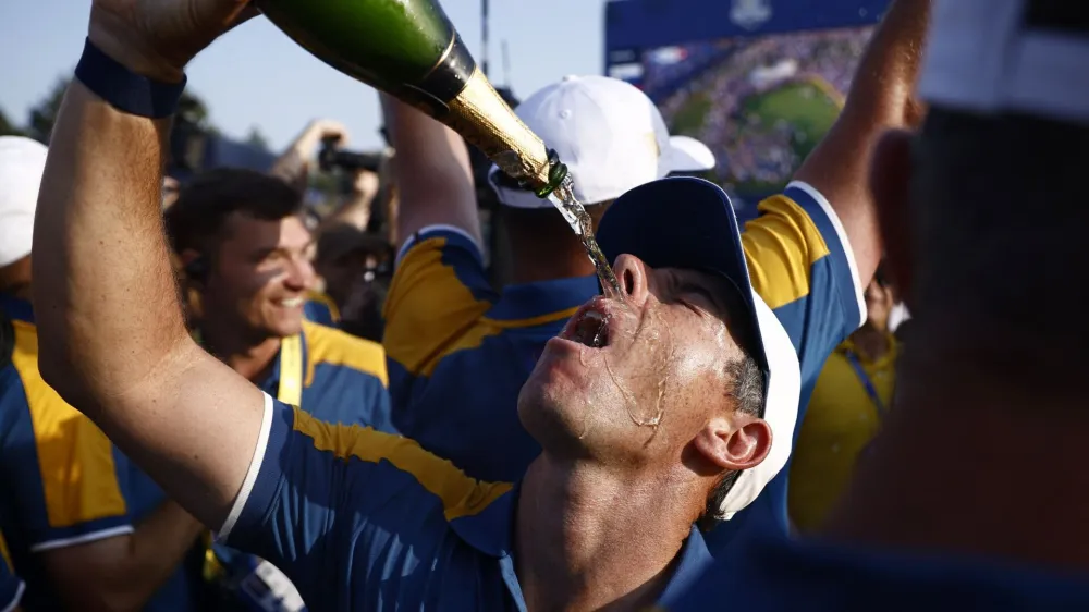 Golf - The 2023 Ryder Cup - Marco Simone Golf & Country Club, Rome, Italy - October 1, 2023 Team Europe's Rory McIlroy pours sparkling wine over his face on the 18th green as he celebrates after winning the Ryder Cup REUTERS/Guglielmo Mangiapane