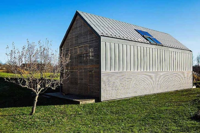 Preprosta hiša v Radovljici z ovojem iz lesenih žaluzij kot aluzija na kmečki dom  