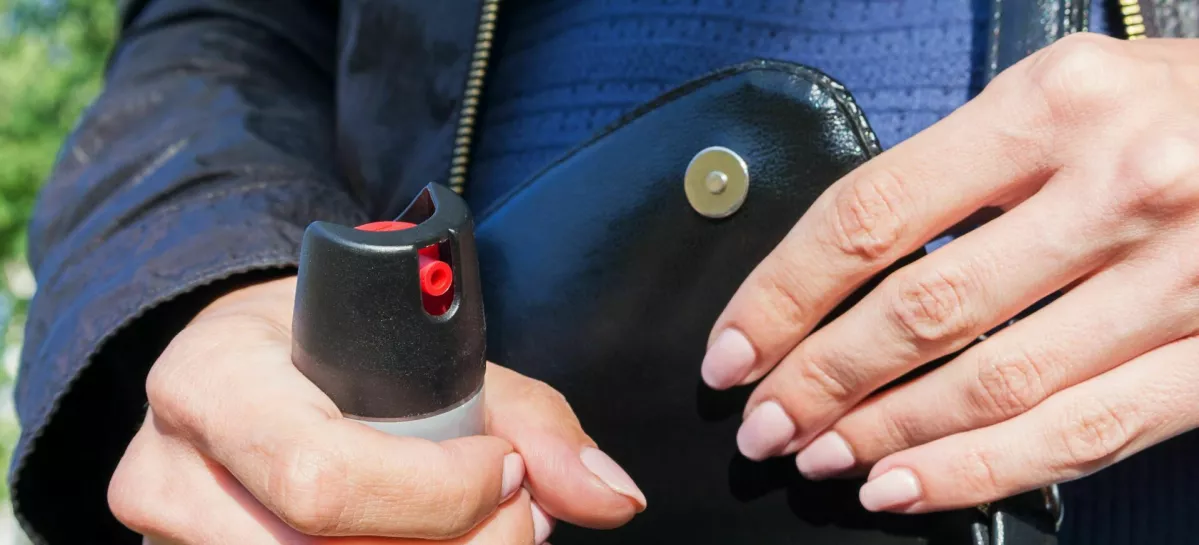 A young woman pulls a can of tear gas or bottle of pepper spray out of her purse. Means of self-defense, protection from robbery and rape.. Selective focus, close-up. / Foto: Evgen_prozhyrko