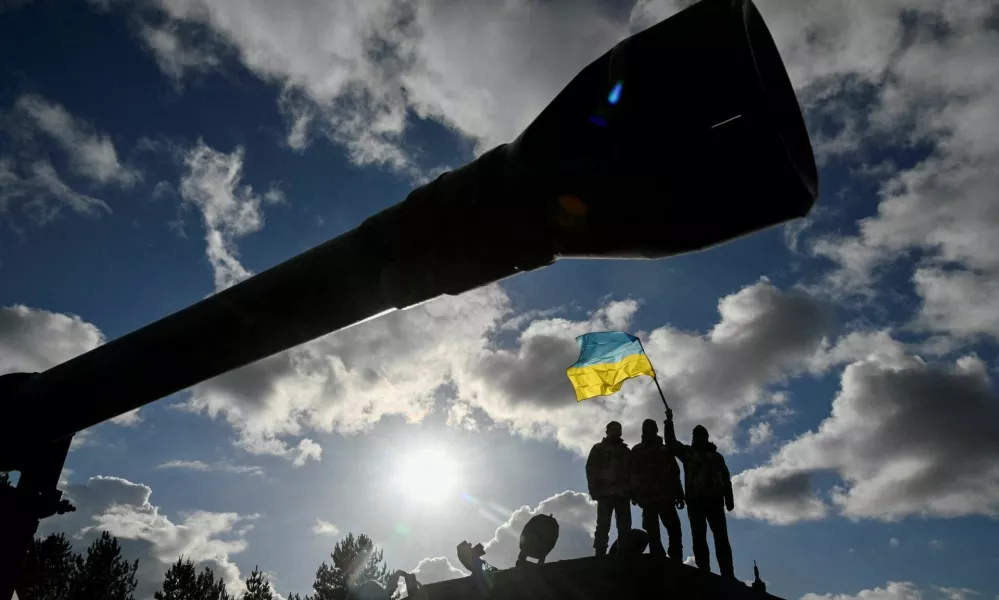 FILE PHOTO: Ukrainian personnel hold a Ukrainian flag as they stand on a Challenger 2 tank during training at Bovington Camp, near Wool in southwestern Britain, February 22, 2023. REUTERS/Toby Melville/File Photo