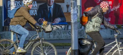 Cyclists ride past a poster of incumbent President Zoran Milanovic ahead of the presidential election in Zagreb, Croatia, Thursday, Dec. 26, 2024. (AP Photo)