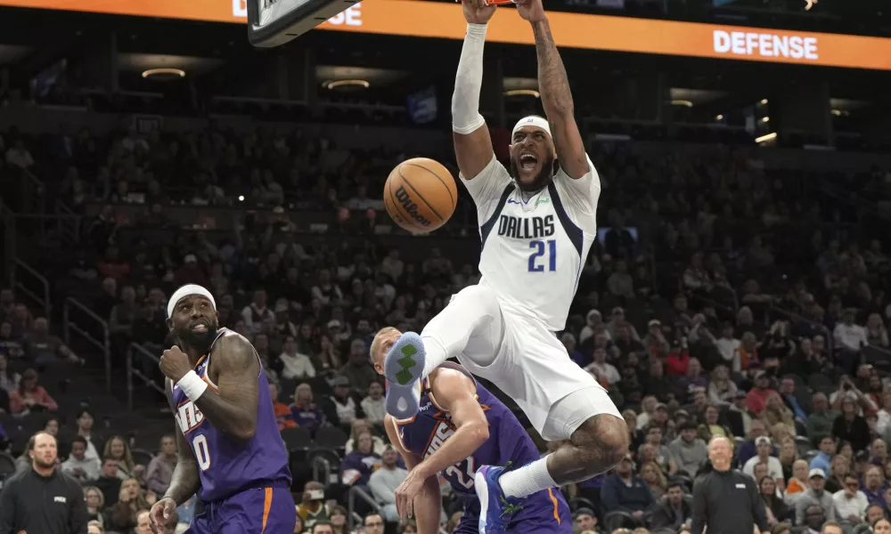 Dallas Mavericks center Daniel Gafford dunks over Phoenix Suns forward Ryan Dunn (0) and center Mason Plumlee during the second half of an NBA basketball game, Friday, Dec. 27, 2024, in Phoenix. Dallas won 98-89. (AP Photo/Rick Scuteri)