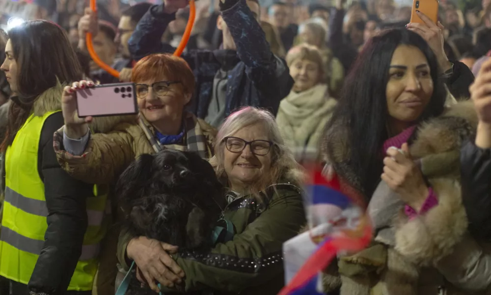 A person carries a dog as she and others await the arrival of university students to the town of Nis, Serbia, to protest the deaths of 15 people killed in the November 2024 collapse of a train station canopy, Friday, Feb. 28, 2025. (AP Photo/Marko Drobnjakovic)