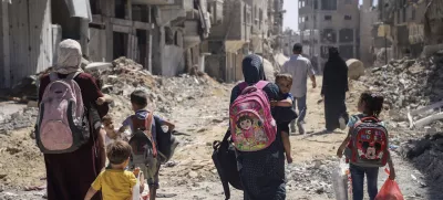 FILE - Palestinian women and their children walk though destruction in the wake of an Israeli air and ground offensive in Jebaliya, northern Gaza Strip after Israeli forces withdrew from the area, on May 31, 2024. (AP Photo/Enas Rami)