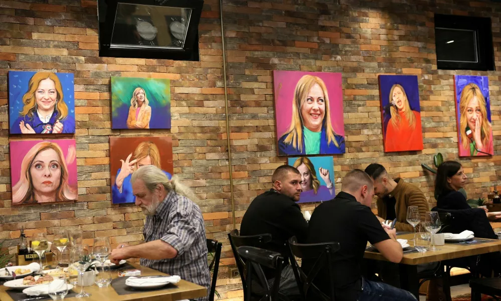 Customers eat a meal as portrait paintings by artist Helidon Haliti of Italy's Prime Minister Giorgia Meloni hang on the walls of "Trattoria Meloni" just outside a migrant processing camp set up by the Italian government, in Shengjin, Albania, October 15, 2024. REUTERS/Florion Goga