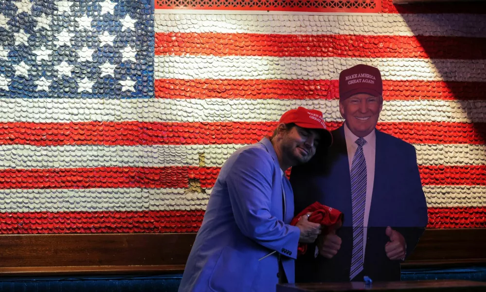 A supporter of Republican presidential nominee former U.S. President Donald Trump embraces a cardboard cut-out of Trump as he reacts to election results while attending the New York Young Republican Club watch party during the 2024 U.S. presidential election, in Manhattan, New York City, U.S., November 6, 2024. REUTERS/Andrew Kelly