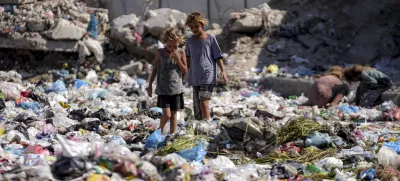 Displaced kids sort through trash at a street in Deir al-Balah, central Gaza Strip, Thursday, Aug. 29, 2024. (AP Photo/Abdel Kareem Hana)